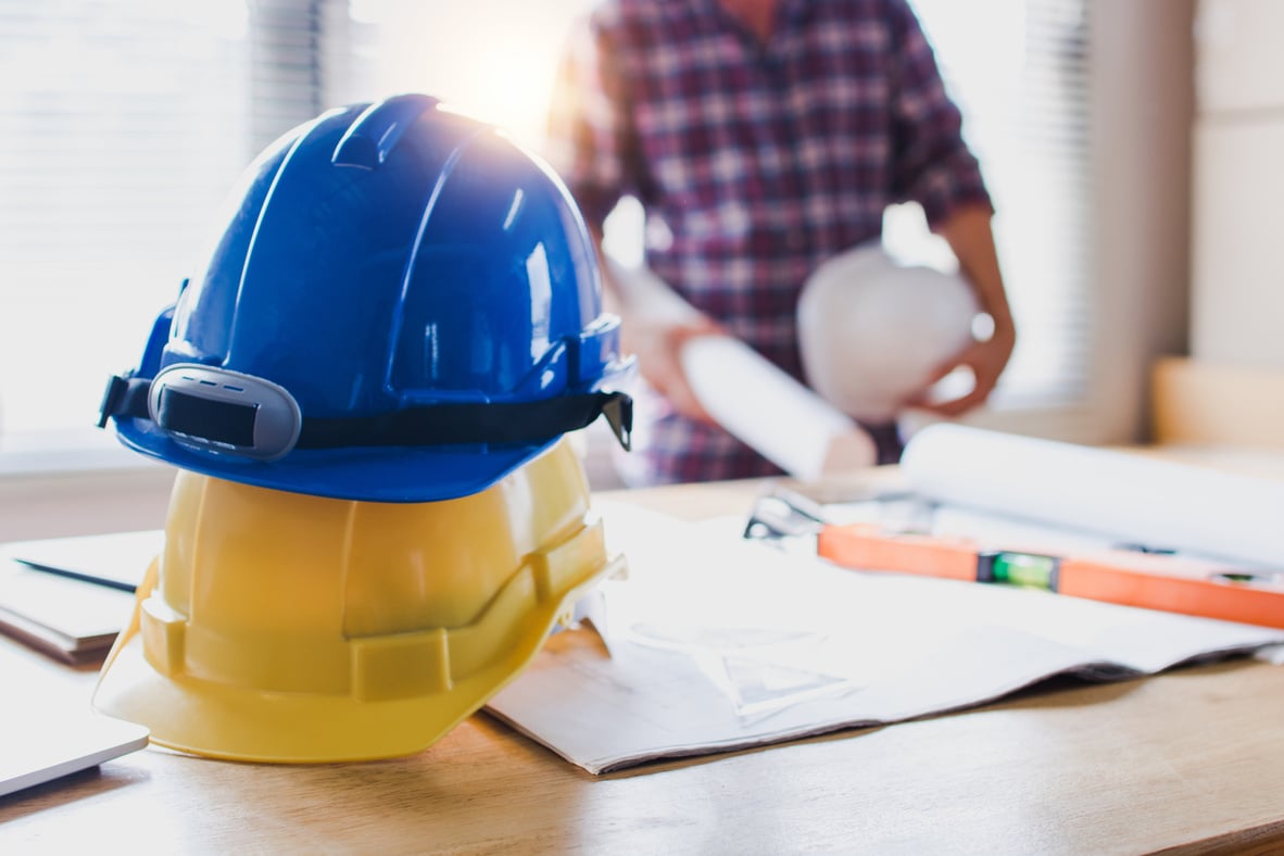 Construction Safety Helmets on Table with Engineer Holding Bluep